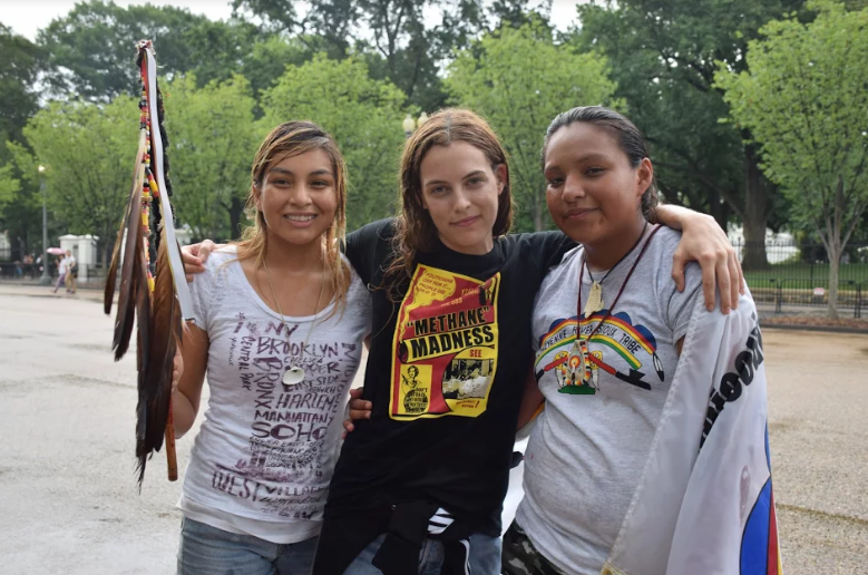 Actress Riley Keough poses with runners Jasilyn Charger (right) and Jasilea Rose Charger (left) during a break in marching.